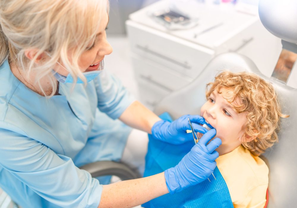 Pretty little boy in dental office, having his teeth checked by female dentist